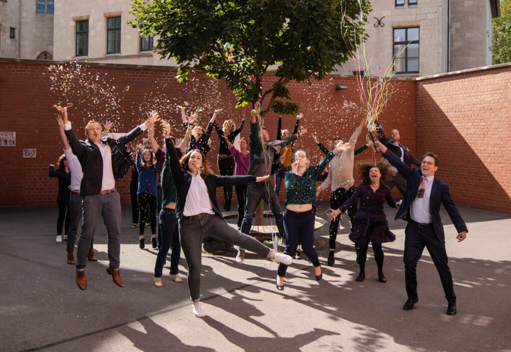 Menschen jubeln und springen in die Luft, sie werfen Konfetti