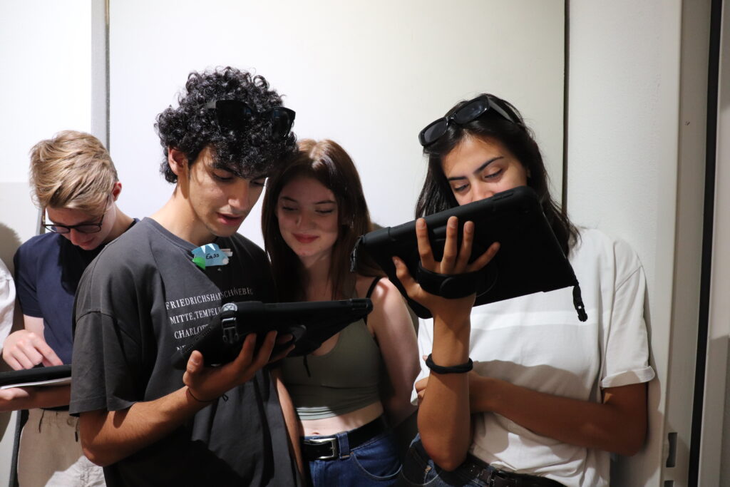 drei junge Menschen schauen auf ein Tablet